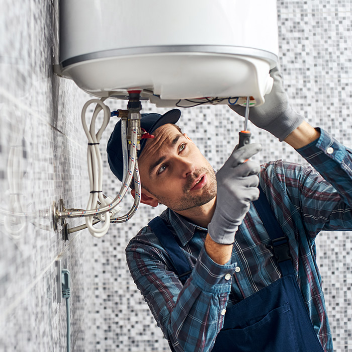 plumber installing new electric water heater system at bathroom interiors dallas tx